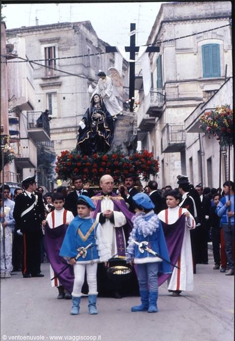 Religious street procession: sacred statues with flowers, priest and children in costume