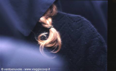 Blonde braid tied with metal ring, shoulder covered by dark blue sweater