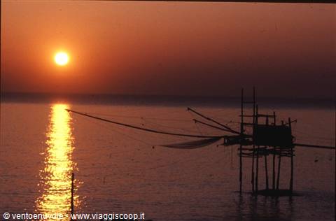 Wooden stilt fishing platform, low sun reflected on calm sea
