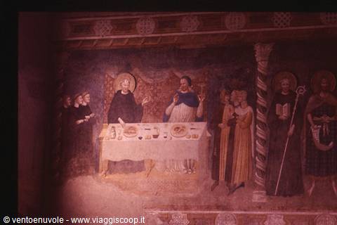 Medieval fresco of saints gathered around a set table, soft lighting