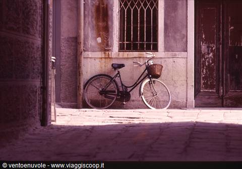 Black bicycle with basket leaning against wall near barred window