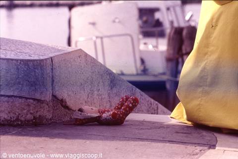 Red polka-dot sandals on stone quay, moored boat behind