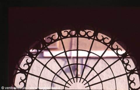 Wrought iron fanlight grille over arched window, filtered light