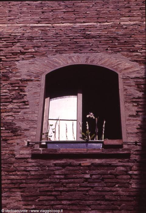 Arched window with flowers on the sill, stone wall