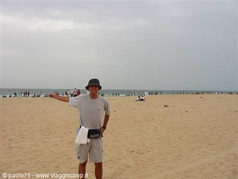 Tourist in hat pointing at the sea on Boa Vista sandy beach