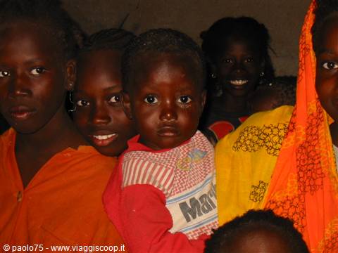 African children in colorful clothes looking at the camera, one smiling