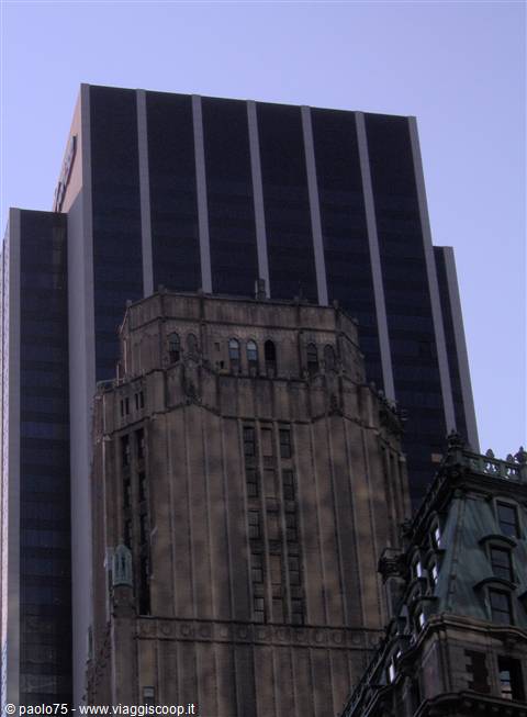 Stone and dark glass skyscrapers stacked under the blue Manhattan sky