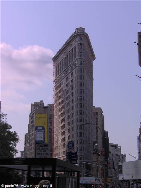 The Flatiron Building in New York among traffic and billboards under violet sky