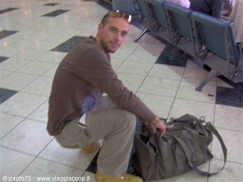 Man crouching opens a travel bag in a waiting area with seats