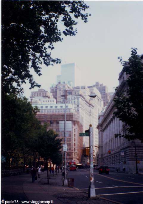 Skyscrapers beyond trees along Broadway, pedestrians on sidewalk, morning light