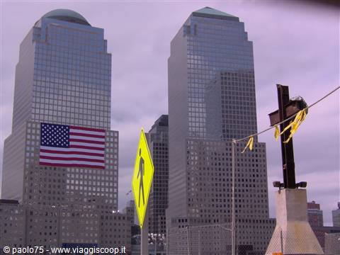 New York, Ground Zero: steel cross with flowers, American flag on skyscrapers