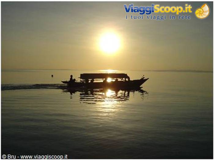 Silhouetted boat gliding on calm sea under the rising sun