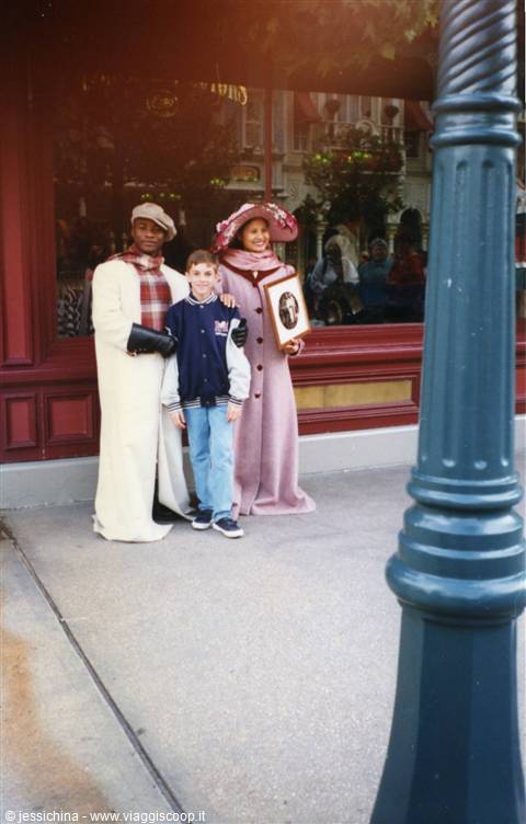 Boy posing with two costumed performers in front of a shop window