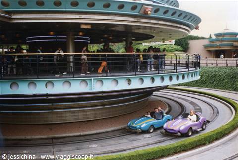 Disneyland Autopia track, colorful cars driving under the rotating platform