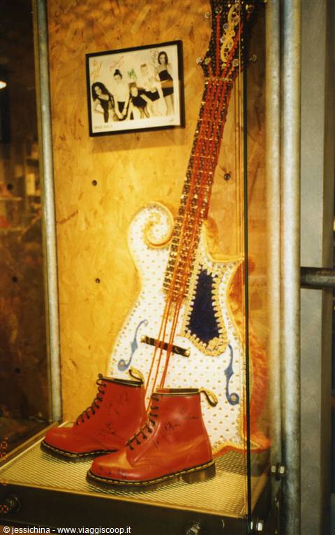 Red boots and a decorated guitar in a shop window with framed photo