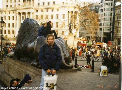 Tourists on the bronze lion in Trafalgar Square, London, crowds and classical buildings