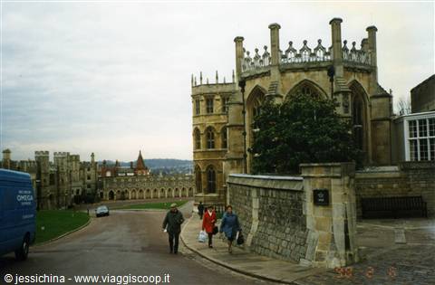 Tourists walk beside the medieval stone walls of Windsor Castle