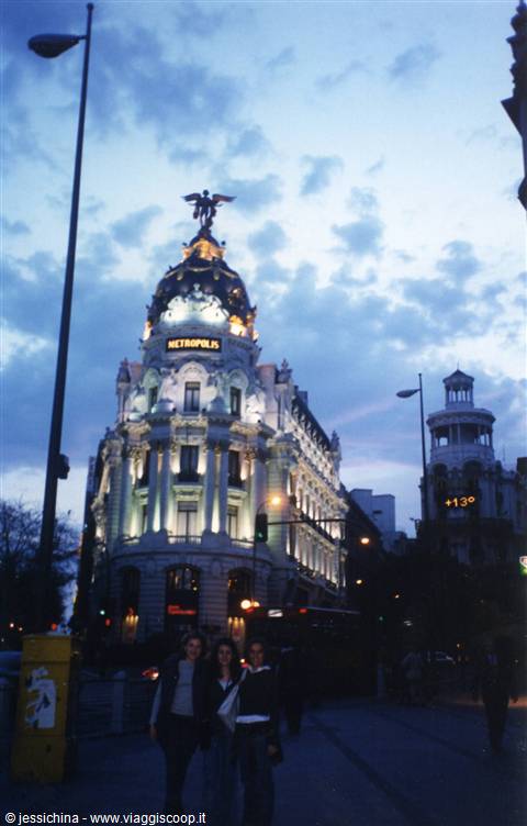 Illuminated Metropolis building on Gran Vía, three girls walking by