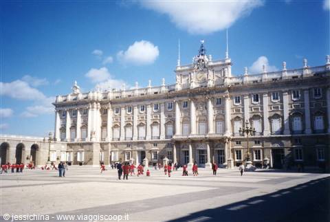 Royal Palace of Madrid, light stone facade, tourists walking in sunny square
