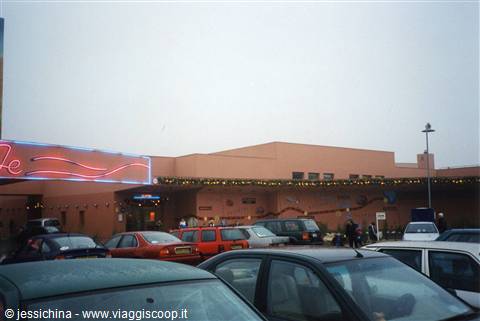 Cars parked in front of a pink building with a neon sign