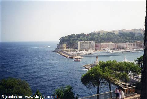 Yachts moored in Monaco harbor, colorful waterfront buildings, deep blue sea