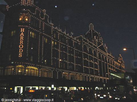Harrods at night, historic facade lit by thousands of golden lights, traffic below