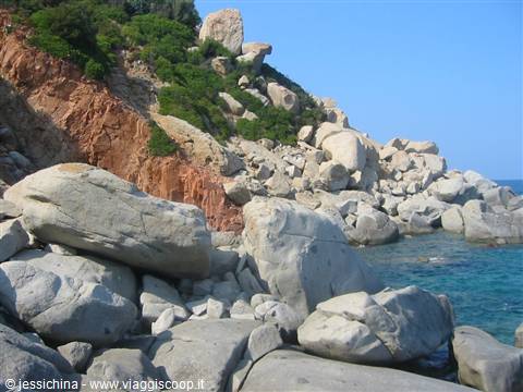 Smooth granite boulders and reddish cliffs on Caprera, turquoise sea