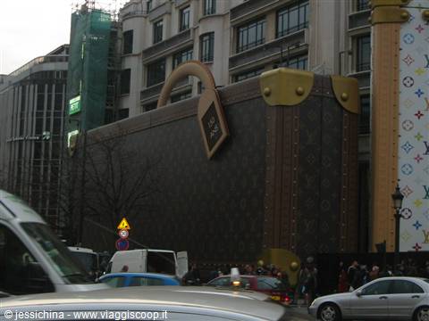 Giant suitcase-shaped facade with monogram pattern, traffic and pedestrians on the Champs-Élysées