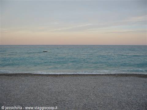 Grey pebble beach, turquoise waves and soft pink sky at early morning