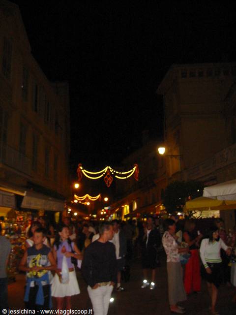 Crowded night market street with yellow festival lights and stall lamps