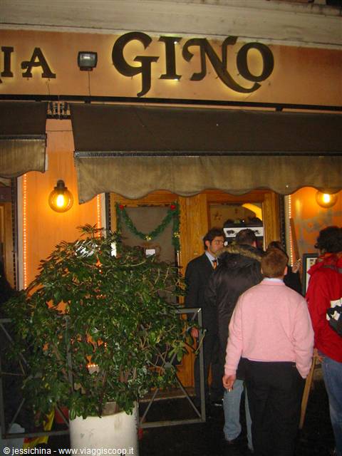 People queue at Gino restaurant entrance under warm lights and Christmas garlands