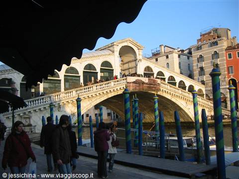 Tourists beside the striped poles on the Grand Canal, Rialto Bridge, Venice