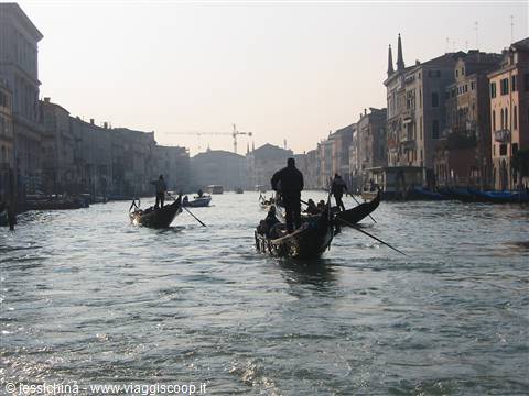 Gondoliers rowing on the Grand Canal among historic Venice palaces in morning haze