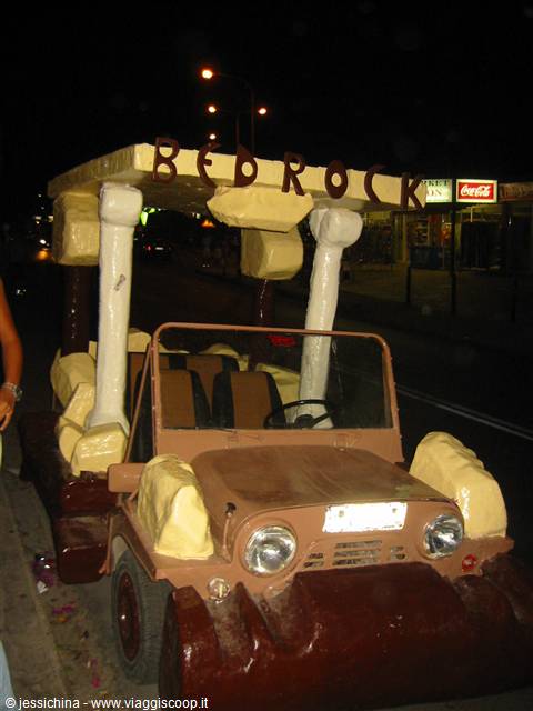 Jeep decorated like the Flintstones with Bedrock sign, on a street at night