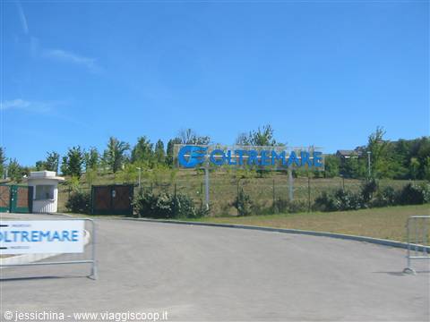 Oltremare park entrance: blue signs on green lawn, clear sky