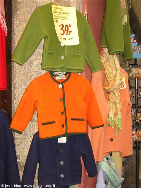 Colorful wool children's jackets hanging at a market stall with a price tag