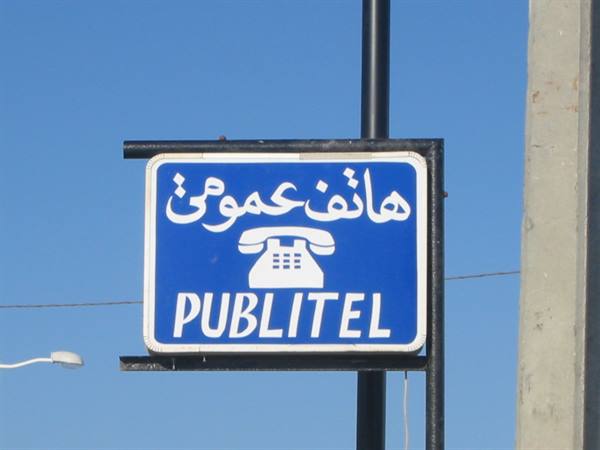 Blue Publitel sign with white telephone icon and Arabic text against clear sky