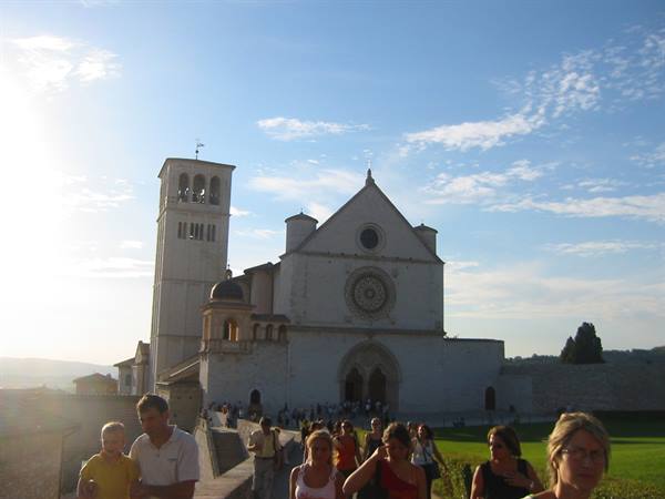 Tourists walk down the steps in front of the Basilica of Saint Francis, Assisi