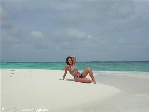 Woman in bikini posing on white sand before the turquoise sea