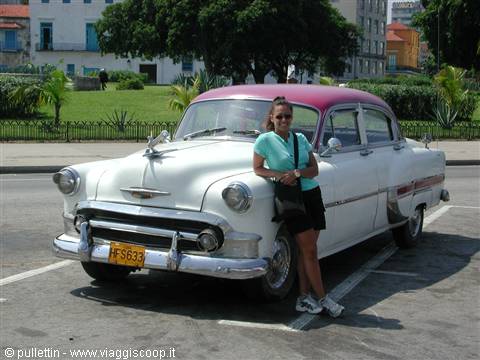 Woman leaning on a vintage white and fuchsia Chevrolet parked near Havana's El Malecón