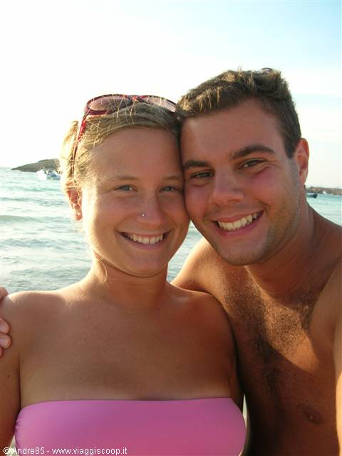 Smiling couple at the beach, she wears pink bikini and sunglasses on head