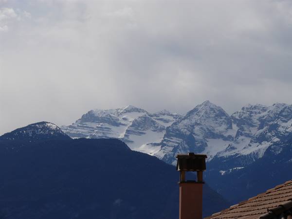 Brick chimney in front of snowy peaks under cloudy sky