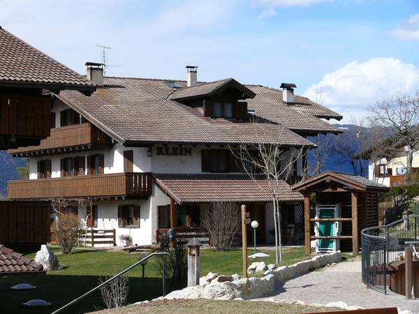 Wooden and plaster house with overhanging roofs and balconies, grassy courtyard