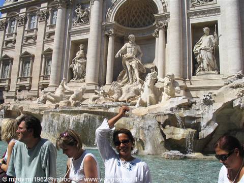 Tourists in front of the Trevi Fountain, baroque statues and flowing water