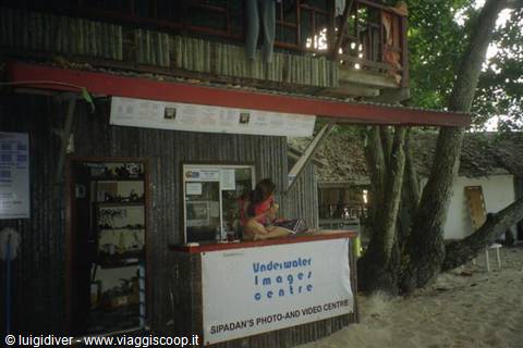 Child sitting at the Sipadan Underwater Images Centre photo counter among wood and sand