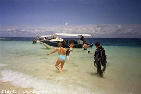 divers with gear and swimmers in turquoise water in front of boats