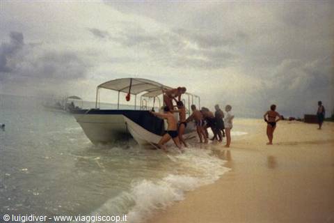 Tourists push a covered boat onto the beach under cloudy skies
