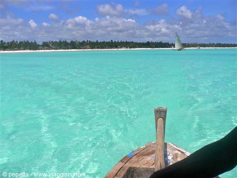 Wooden boat bow on turquoise water, sailboat near the beach