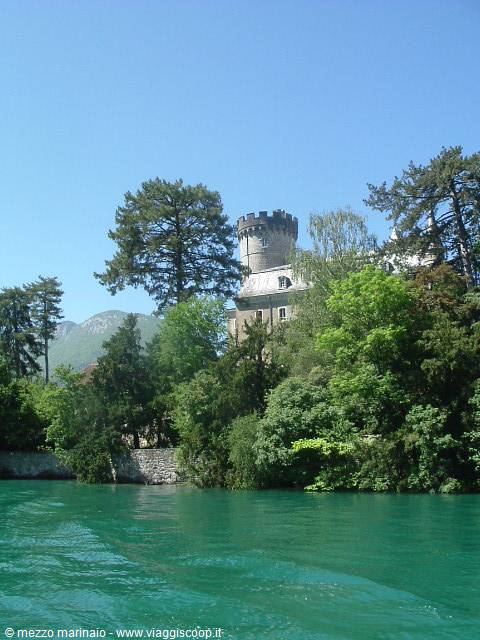 Crenellated castle tower among trees overlooking the lake's green waters