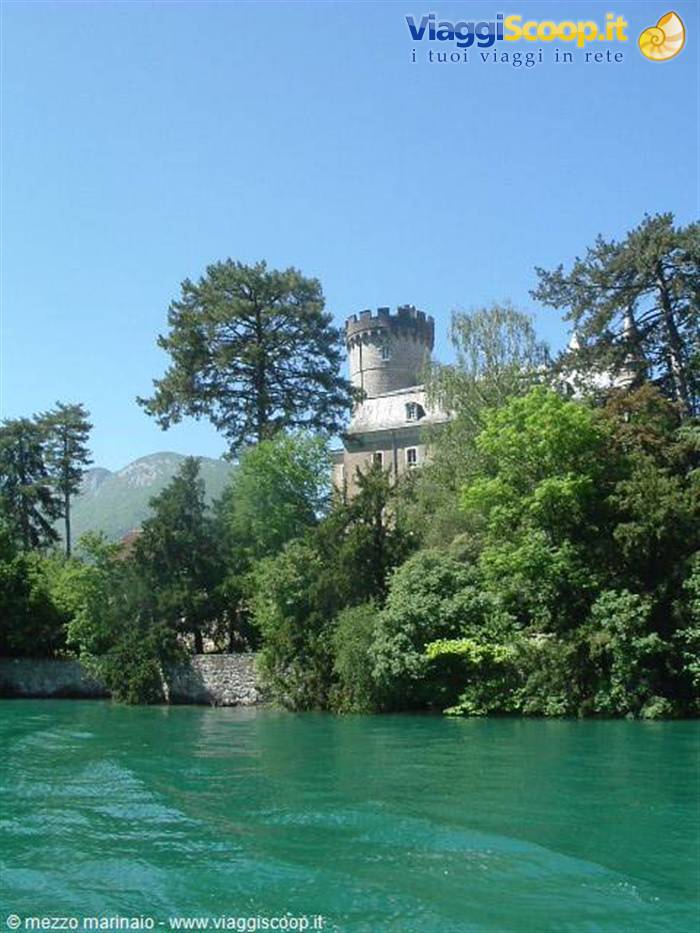 Crenellated castle tower among trees overlooking the lake's green waters